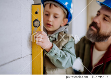 Father and his little son working on their unfinished house. 102795393