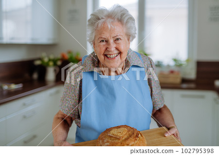 Portrait of senior woman with fresh baked bread. Portrait of senior woman with fresh baked bread. 102795398