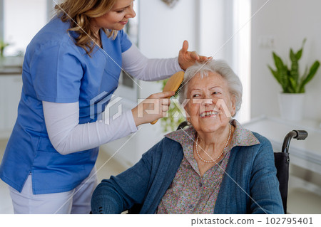 Nurse doing hairstyle to her senior woman client. 102795401