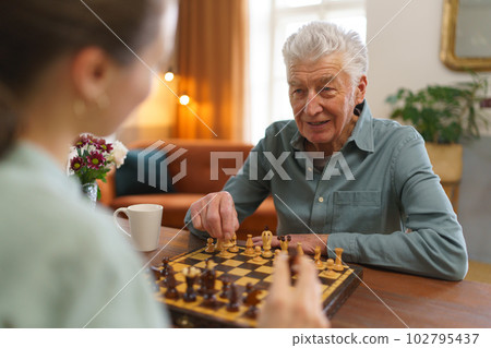 Senior man playing chess with his granddaughter. 102795437