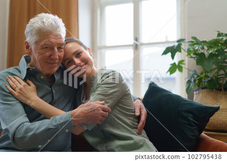 Granddaughter hugging her grandfather in their home. 102795438