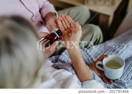 Close up of senior man giving medicines to his ill wife. Close up of senior man giving medicines to his ill wife. 102795466