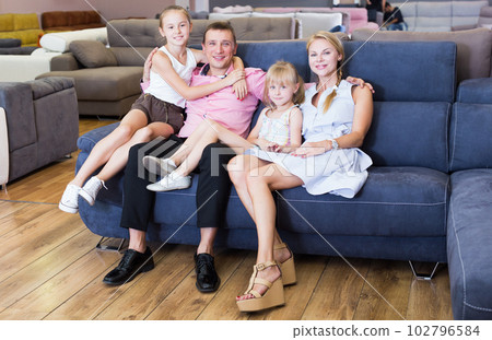 Family is pleased by new sofa in store. 102796584