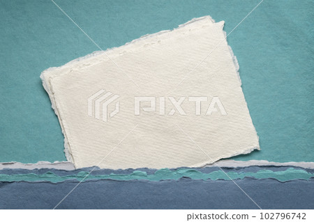 small sheet of blank white Khadi rag paper from India against abstract landscape in blue tones 102796742