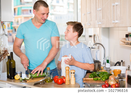Man with his son are cooking soup in the kitchen Man with his son are cooking soup in the kitchen 102796816