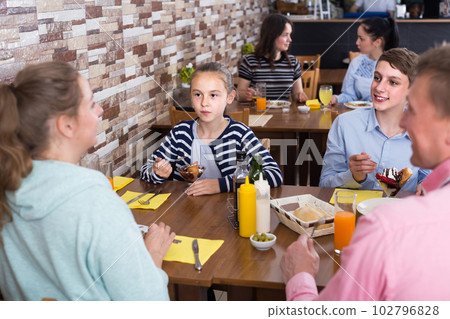 family with teenage children enjoying meal in cafe 102796828