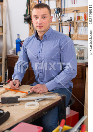 young male carpenter working wood plank at workshop young male carpenter working wood plank at workshop 102796911