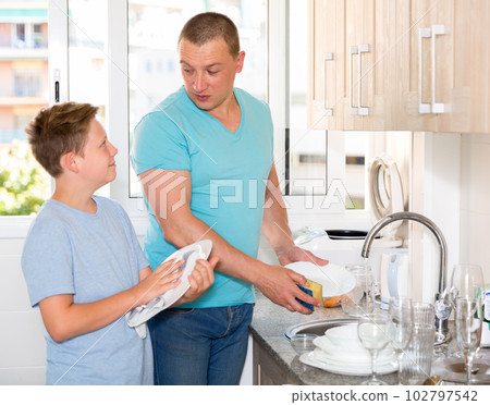 Boy and his father are helling mother and washing dishes 102797542