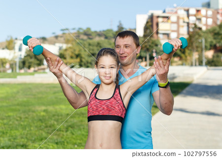 Girl with father exercising with dumbbells 102797556