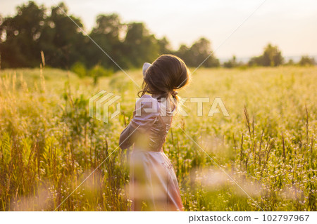 girl standing in the field in a pink dress girl standing in the field in a pink dress 102797967