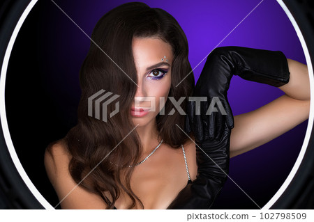 Female portrait of a young brunette girl with a beautiful evening make-up. The girl has gloves on her hands Female portrait of a young brunette girl with a beautiful evening make-up. The girl has gloves on her hands 102798509