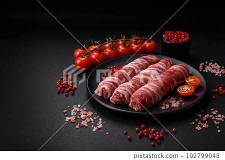 Raw minced meat wrapped in bacon with salt and spices or cevapcici Raw minced meat wrapped in bacon with salt and spices or cevapcici 102799048