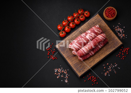 Raw minced meat wrapped in bacon with salt and spices or cevapcici Raw minced meat wrapped in bacon with salt and spices or cevapcici 102799052