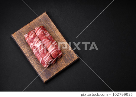 Raw minced meat wrapped in bacon with salt and spices or cevapcici Raw minced meat wrapped in bacon with salt and spices or cevapcici 102799055