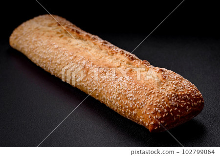 Crispy wheat flour baguette with sesame seeds on a wooden cutting board Crispy wheat flour baguette with sesame seeds on a wooden cutting board 102799064