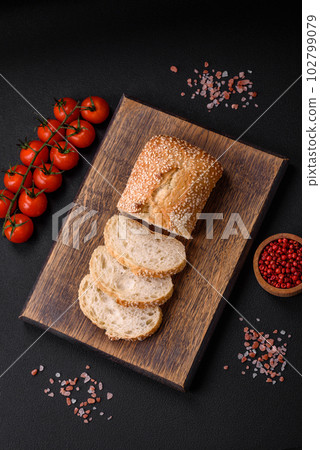 Crispy wheat flour baguette with sesame seeds on a wooden cutting board 102799079