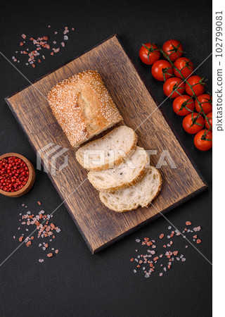 Crispy wheat flour baguette with sesame seeds on a wooden cutting board 102799081