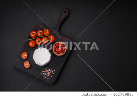Delicious fresh brie cheese in the form of a mini head with cherry tomatoes 102799083