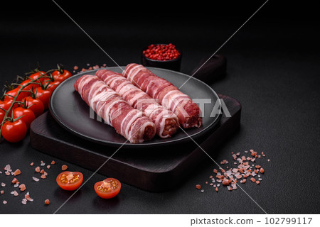 Raw minced meat wrapped in bacon with salt and spices or cevapcici Raw minced meat wrapped in bacon with salt and spices or cevapcici 102799117