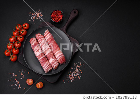 Raw minced meat wrapped in bacon with salt and spices or cevapcici Raw minced meat wrapped in bacon with salt and spices or cevapcici 102799118