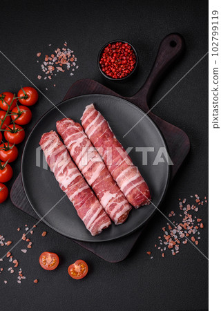 Raw minced meat wrapped in bacon with salt and spices or cevapcici Raw minced meat wrapped in bacon with salt and spices or cevapcici 102799119