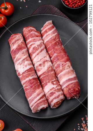 Raw minced meat wrapped in bacon with salt and spices or cevapcici Raw minced meat wrapped in bacon with salt and spices or cevapcici 102799121