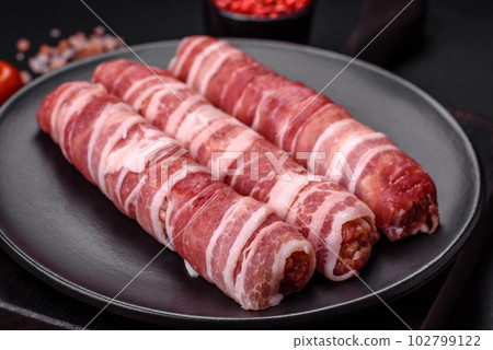 Raw minced meat wrapped in bacon with salt and spices or cevapcici Raw minced meat wrapped in bacon with salt and spices or cevapcici 102799122
