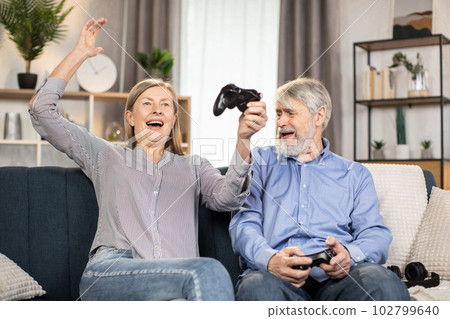 Senior people playing video games with controllers indoors Senior people playing video games with controllers indoors 102799640