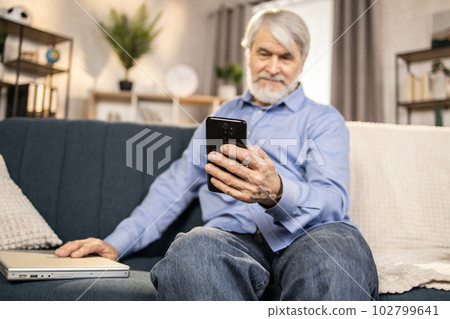 Elderly adult using leisure time for smart gadgets at home Elderly adult using leisure time for smart gadgets at home 102799641