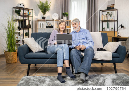 Elderly adults watching video on laptop in living room 102799764