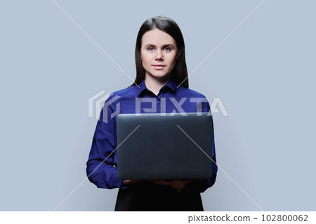 Young business woman posing with laptop, on grey background 102800062