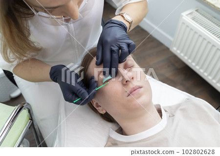 Lashmaker Sets Silicone Roller On Eyelid Client For Eyelash Lamination Treatment Procedure In Beauty Salon. Curling, Staining, Extension Procedures For Lashes. Horizontal Plane. Step By Step. Topview 102802628