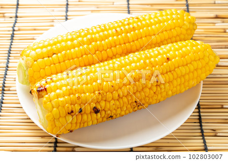 Grilled corn with butter and soy sauce. Summer image with background blinds. 102803007