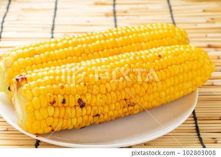 Grilled corn with butter and soy sauce. Summer image with background blinds. 102803008