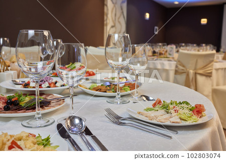 Classy table with a bouquet. Luxury dining set with cutlery, serviette, crockery and covered with a tablecloth in restaurant. 102803074