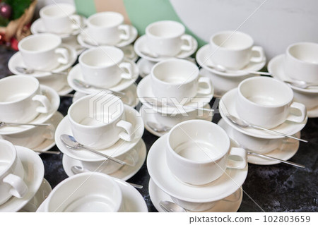 Stacked empty teacups with teaspoons at a function over. Stacked empty teacups with teaspoons at a function over. 102803659