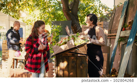 Diverse farmers helping customers with produce and healthy food, vendors selling homegrown fruits and veggies. Consumers talking to farmers about organic products, stall holders. 102804268