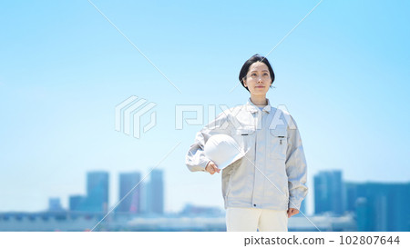 A woman in work clothes holding a helmet A woman in work clothes holding a helmet 102807644