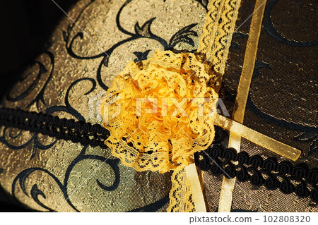 A beautiful yellow-orange lace artificial flower sewn onto a decorative cushion satin fabric. Blue dense braid with thin polyester lace. Decoration of decorative pillowcases. Women's needlework 102808320