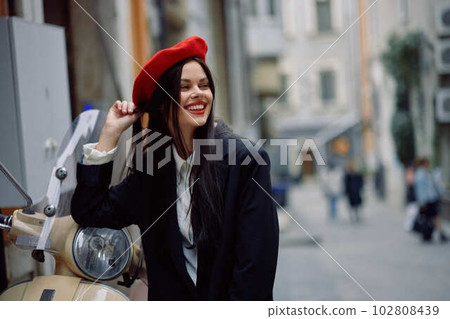Beautiful woman smile standing with an old vintage motorcycle on a city street, stylish fashion look of clothes, vacation and travel. Beautiful woman smile standing with an old vintage motorcycle on a city street, stylish fashion look of clothes, vacation and travel. 102808439