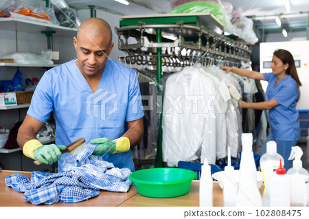 Focused man drycleaner removing spots and stains 102808475