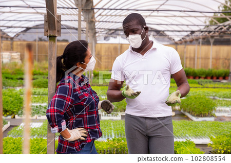 Two garden workers in masks discussing working process 102808554