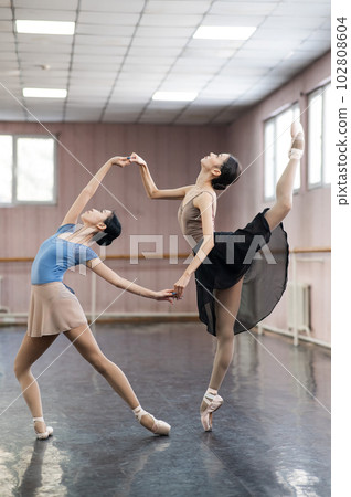 Two Asian ballerinas are dancing in the class.  102808604