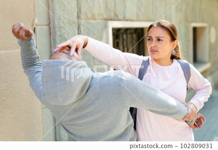 Strong woman using forceful blow in the eyes of rapist on street 102809031