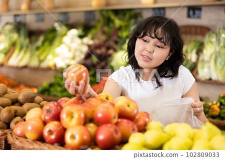 Delighted young woman purchaser choosing apples in grocery store 102809033