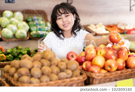 Delighted young woman purchaser choosing apples in grocery store 102809180