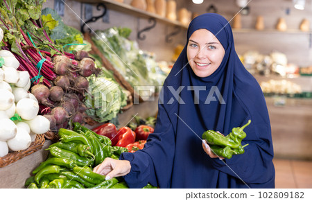 Delighted young Muslim woman purchaser choosing pepper in grocery store Delighted young Muslim woman purchaser choosing pepper in grocery store 102809182