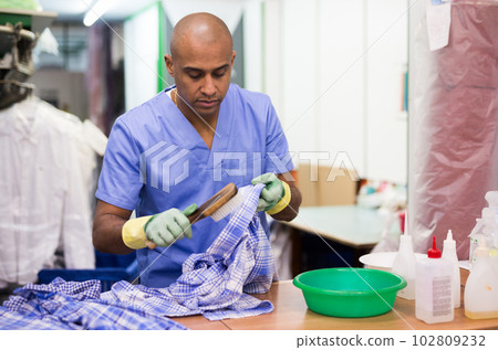 Skilled man working in dry cleaner Skilled man working in dry cleaner 102809232