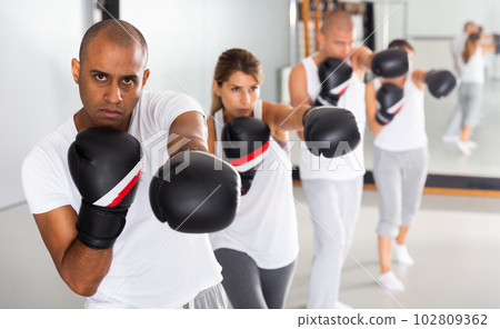 Hispanic man in boxing gloves during group self-defense workout 102809362