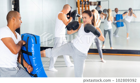 Adult man is training with woman and punching gloves in box gym 102809392